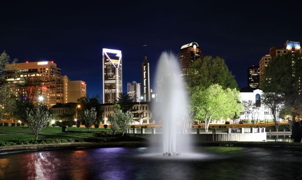 Night view of lit city buildings behind a fountain